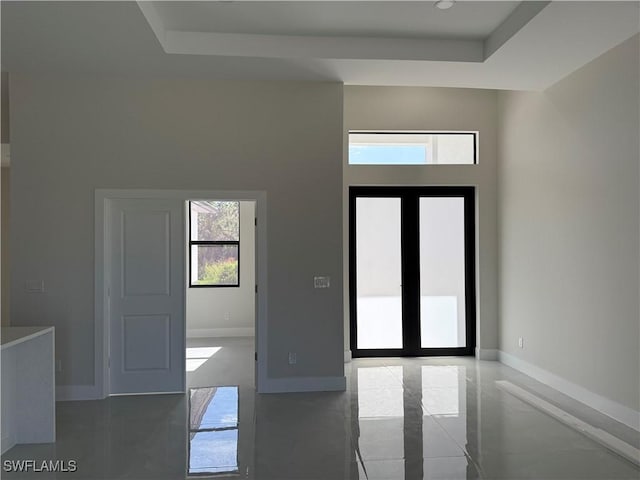 foyer entrance featuring a raised ceiling, a healthy amount of sunlight, and french doors