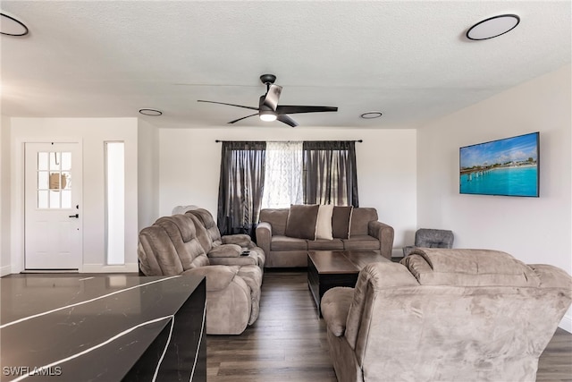 living room with ceiling fan, a textured ceiling, and dark hardwood / wood-style flooring