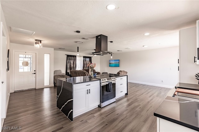 kitchen featuring stainless steel electric stove, white cabinets, island range hood, a kitchen island, and dark hardwood / wood-style floors