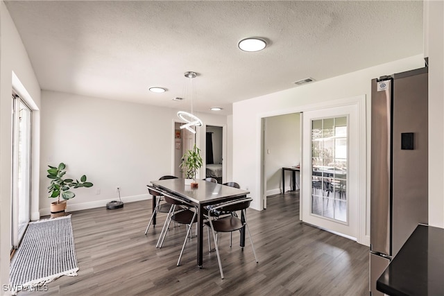 dining area featuring a textured ceiling and dark hardwood / wood-style flooring