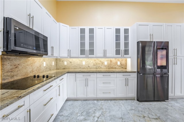 kitchen with light stone counters, stainless steel appliances, backsplash, and white cabinetry