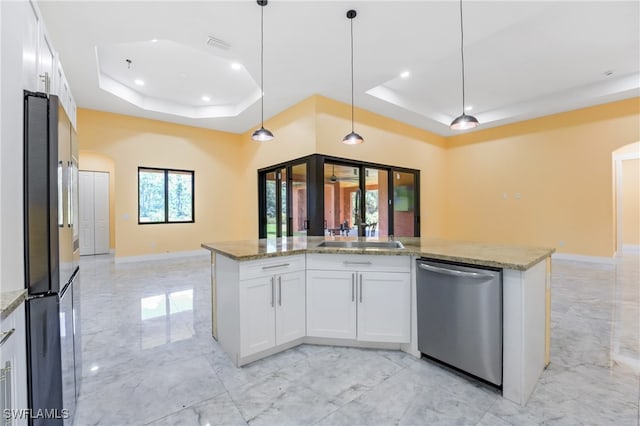 kitchen with white cabinets, light stone counters, a raised ceiling, and appliances with stainless steel finishes