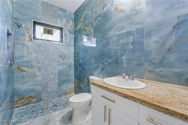 bathroom with tile walls, a tile shower, vanity, and toilet