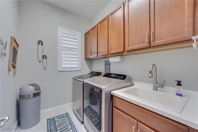 washroom featuring cabinet space, light tile patterned floors, baseboards, washing machine and clothes dryer, and a sink