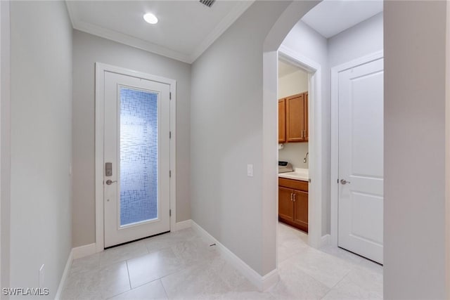 entryway with arched walkways, crown molding, baseboards, and light tile patterned floors