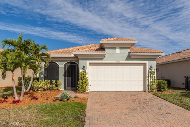 mediterranean / spanish house featuring a garage, decorative driveway, and stucco siding