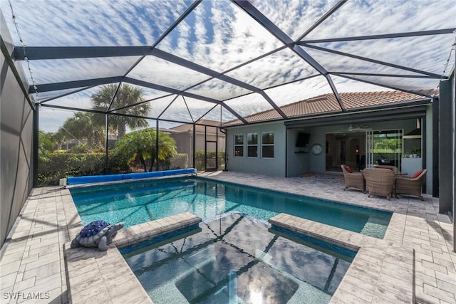 view of swimming pool featuring a pool with connected hot tub, glass enclosure, and a patio