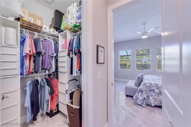 walk in closet featuring marble finish floor and ceiling fan