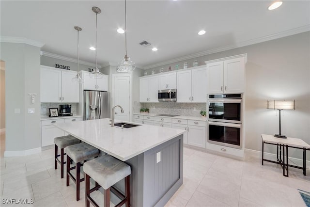 kitchen with stainless steel appliances, white cabinetry, a sink, and a center island with sink