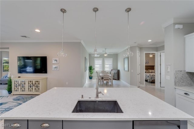 kitchen featuring open floor plan, decorative light fixtures, a sink, and white cabinets