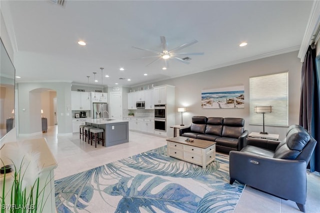 living room featuring ornamental molding, arched walkways, ceiling fan, and recessed lighting