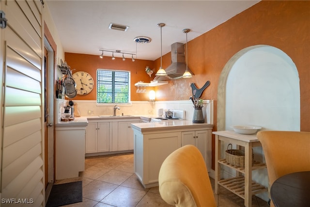 kitchen with white cabinets, island range hood, decorative light fixtures, and sink