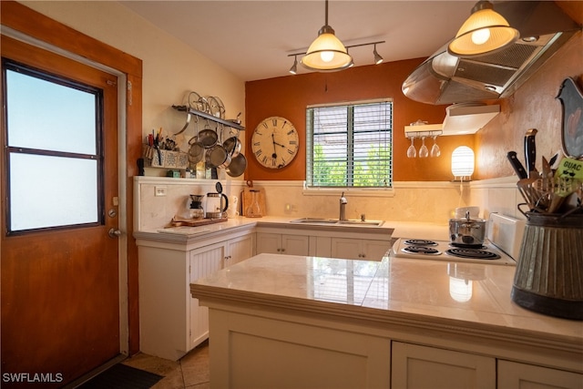 kitchen with kitchen peninsula, sink, pendant lighting, and white cabinets