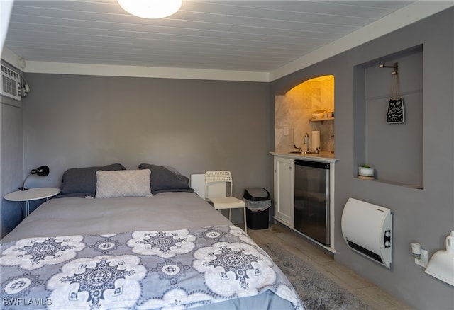 bedroom with stainless steel refrigerator, light wood-type flooring, heating unit, and a wall unit AC