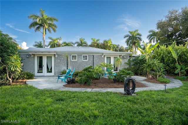 rear view of property featuring french doors and a lawn