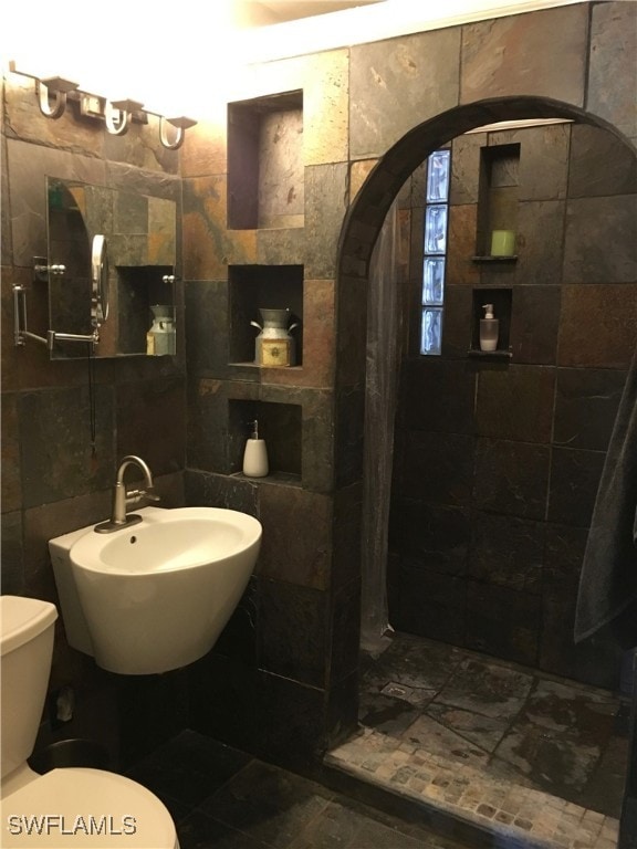 bathroom with tile walls, toilet, and sink