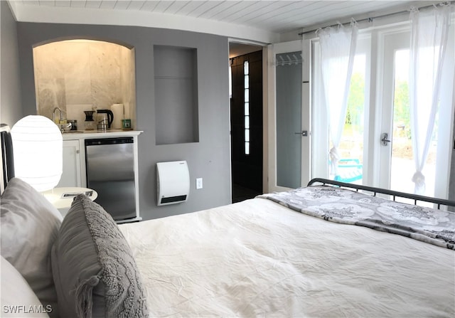 bedroom featuring heating unit, wood ceiling, and stainless steel fridge