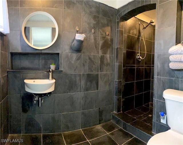 bathroom with sink, tile walls, toilet, and tiled shower