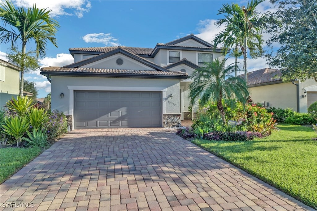 13512 San Georgio Dr, Estero, FL 33928 - mediterranean / spanish home with stucco siding, a tiled roof, decorative driveway, a front yard, and a garage