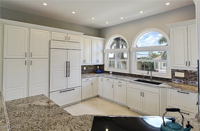 kitchen featuring decorative backsplash, white cabinetry, sink, and paneled fridge