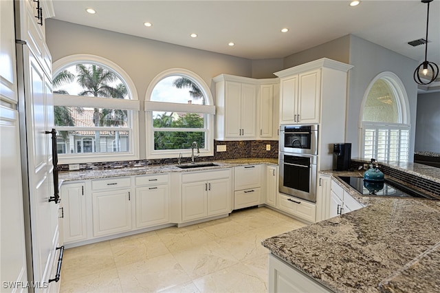 kitchen featuring stainless steel double oven, backsplash, pendant lighting, sink, and white cabinets