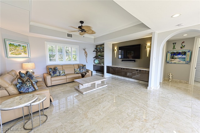 living room with ceiling fan, a raised ceiling, and ornamental molding