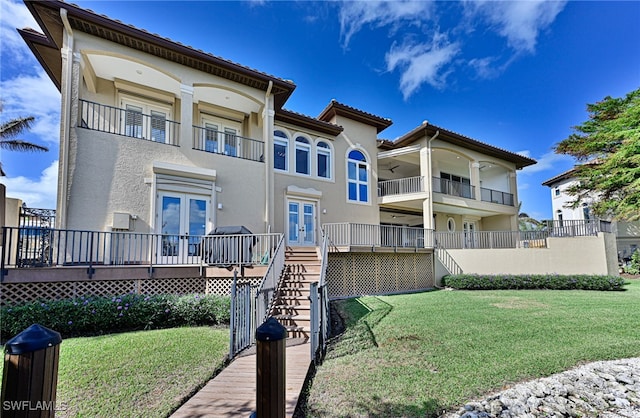 rear view of house featuring a balcony and a yard