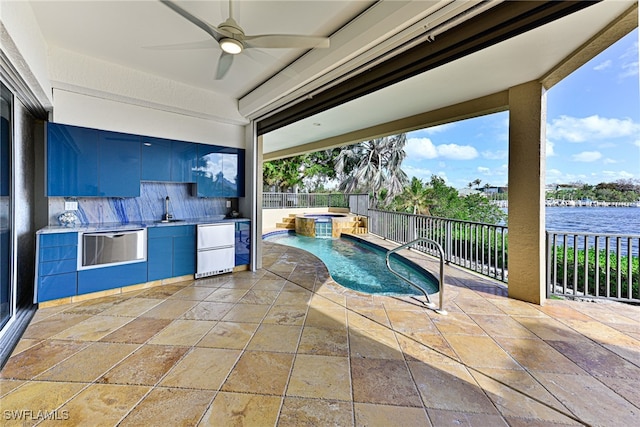 view of pool with an in ground hot tub, a patio, sink, a water view, and ceiling fan