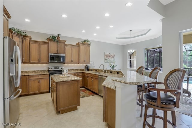 kitchen featuring sink, kitchen peninsula, decorative light fixtures, a breakfast bar area, and appliances with stainless steel finishes