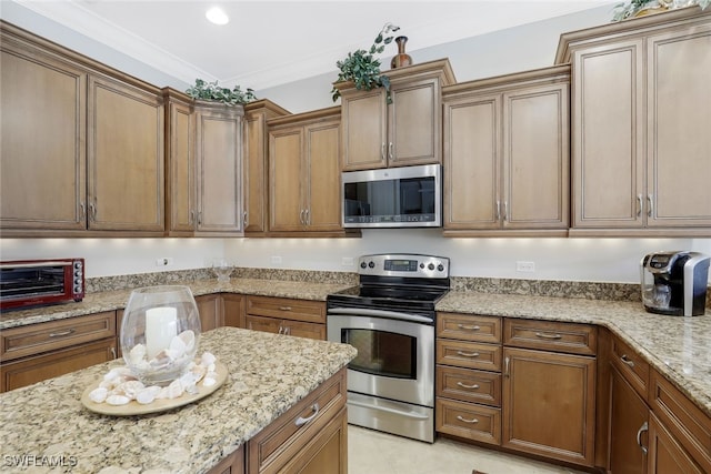 kitchen featuring light tile patterned flooring, light stone counters, ornamental molding, and stainless steel appliances