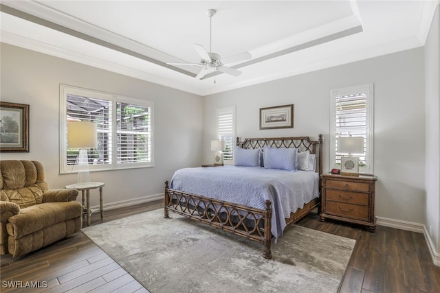 bedroom with ceiling fan, dark hardwood / wood-style flooring, a tray ceiling, and multiple windows