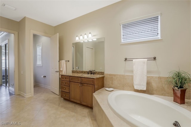 bathroom featuring vanity, tile patterned floors, and tiled tub