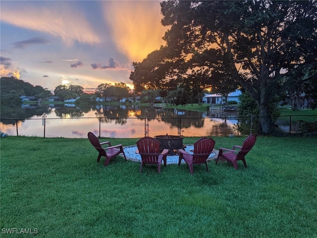 yard at dusk featuring a fire pit and a water view