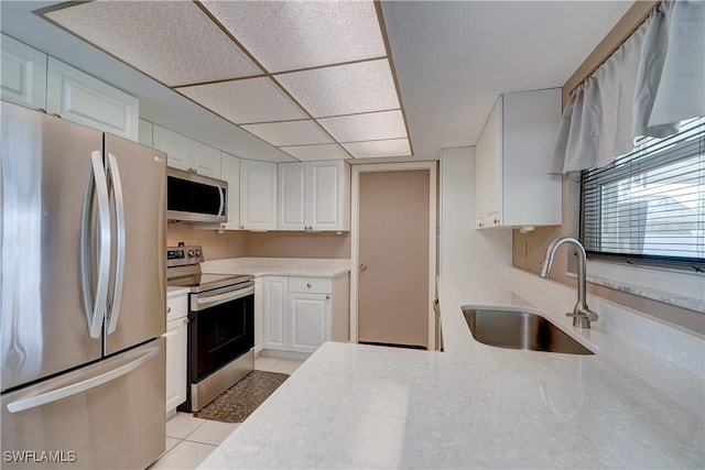 kitchen featuring light tile patterned flooring, appliances with stainless steel finishes, white cabinetry, and sink