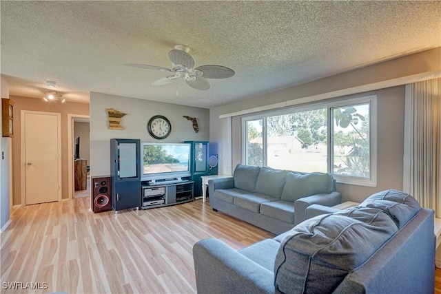 living room with ceiling fan, a textured ceiling, and light hardwood / wood-style flooring