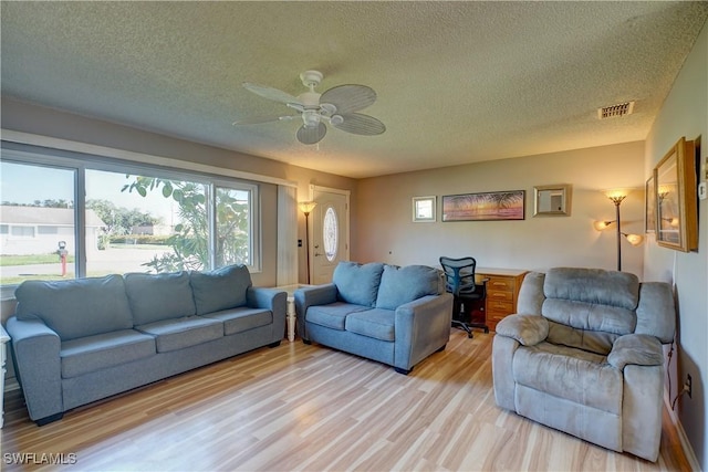 living room featuring ceiling fan, a textured ceiling, and light hardwood / wood-style flooring