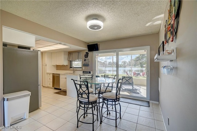 tiled dining room featuring sink and a textured ceiling