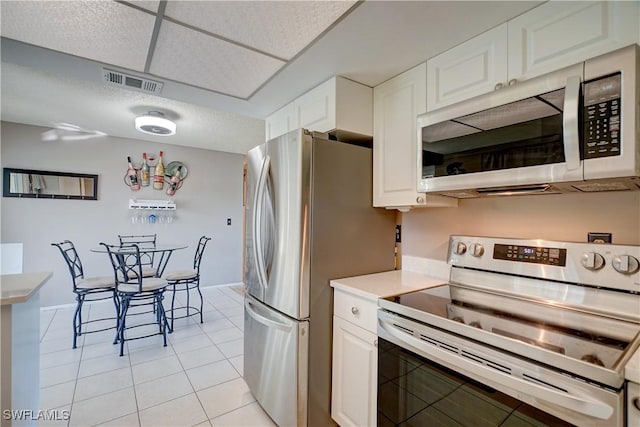 kitchen featuring white cabinetry, stainless steel appliances, and light tile patterned flooring