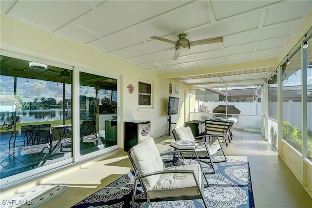 sunroom featuring ceiling fan and a water view