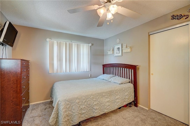 carpeted bedroom with a textured ceiling, ceiling fan, and a closet