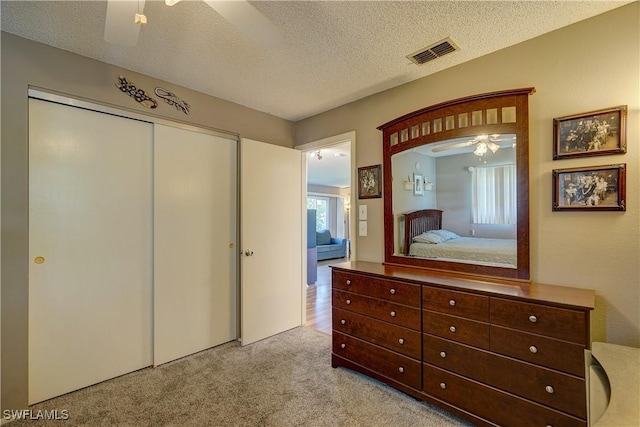 carpeted bedroom featuring ceiling fan, a textured ceiling, and a closet