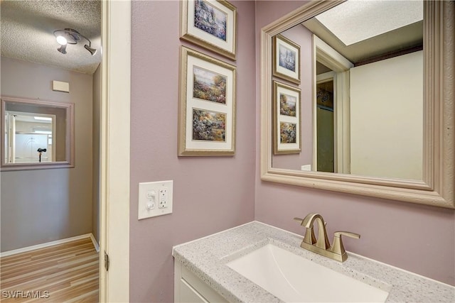 bathroom featuring a textured ceiling, hardwood / wood-style flooring, and vanity