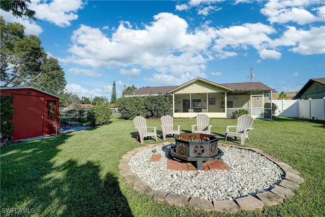 view of yard with a sunroom, an outdoor fire pit, and a storage unit