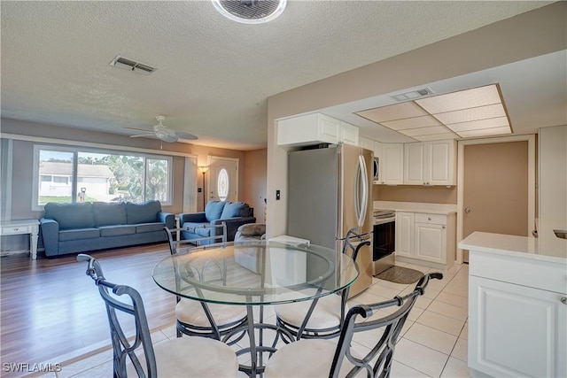 dining room featuring a textured ceiling, ceiling fan, and light tile patterned flooring