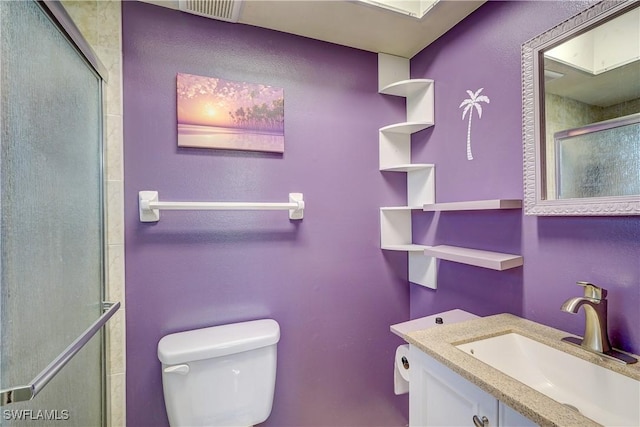 bathroom featuring toilet, a shower with door, and vanity