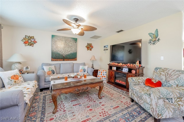 living room with ceiling fan and a textured ceiling