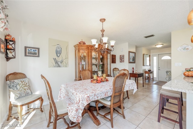 tiled dining space featuring a chandelier and a textured ceiling