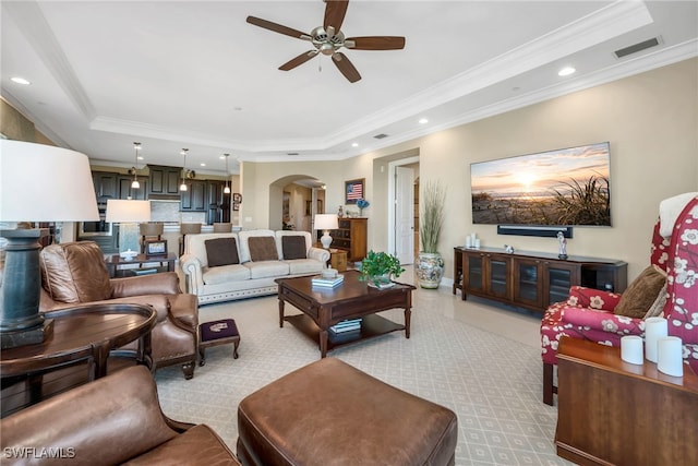 living room with crown molding, ceiling fan, and a tray ceiling