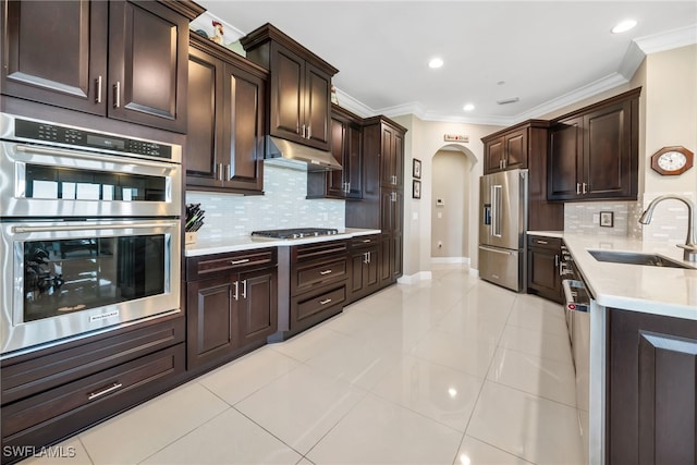 kitchen featuring dark brown cabinetry, sink, crown molding, and stainless steel appliances