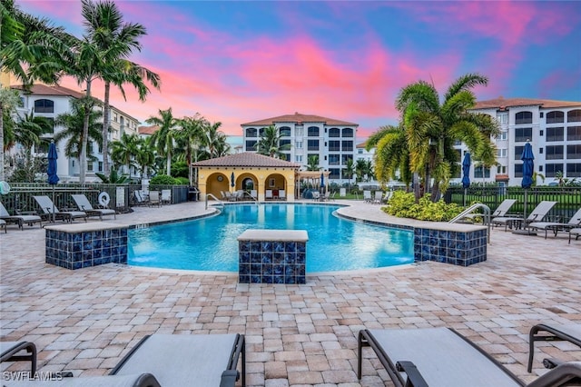 pool at dusk with pool water feature and a patio area